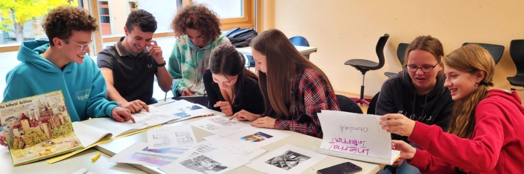 Deutsche und tschechische Schüler sitzen über Arbeitsblättern in beiden Sprachen