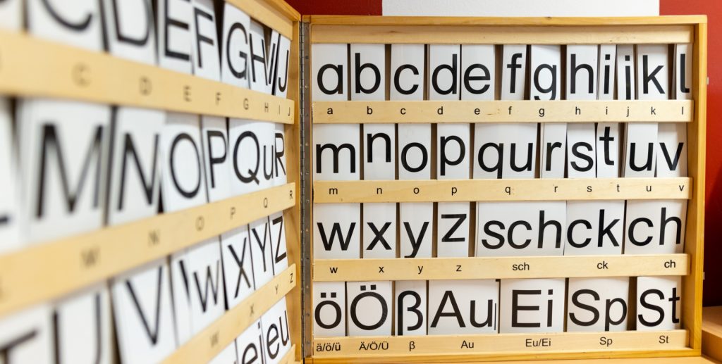 Es ist ein hölzerner Buchstaben-Steckkasten zum Erlernen des Alphabets im Anschnitt zu sehen.