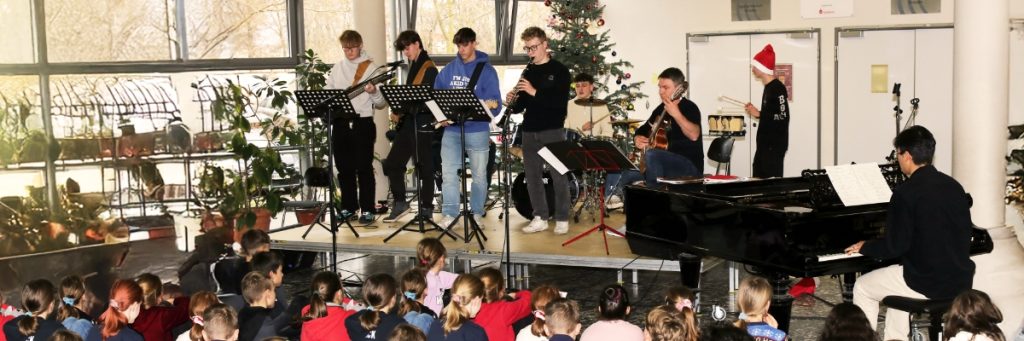 Schüler und Musiklehrer Maik Wagner stehen bei einer Weihnachtsfeier im Sportgymnasium Dresden gemeinsam auf der Bühne.