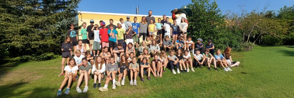 Auf einem kleinen Hügel vor dem Sportgymnasium hat sich Maik Wagners erste Klasse, die er leitet, zum Gruppenbild vor dem Sportgymnasium Dresden zusammengefunden.