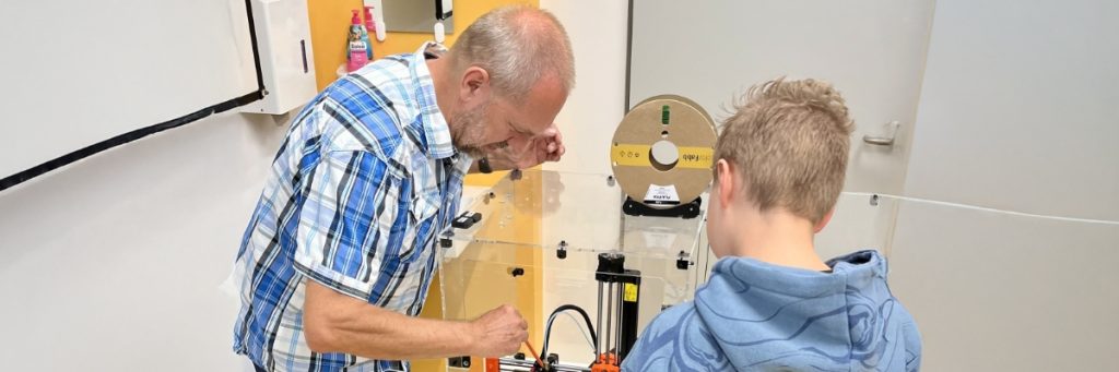 Informatiklehrer Thomas Knapp zeigt einem Schüler den Aufbau einer Maschine.