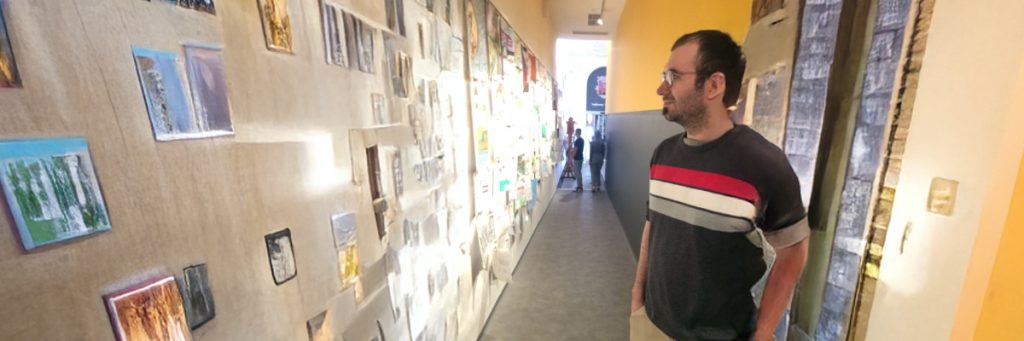 Fremdsprachenassistent Jakub Rudolf steht in einem langen Gang mit einer Fotowand, die er betrachtet.
