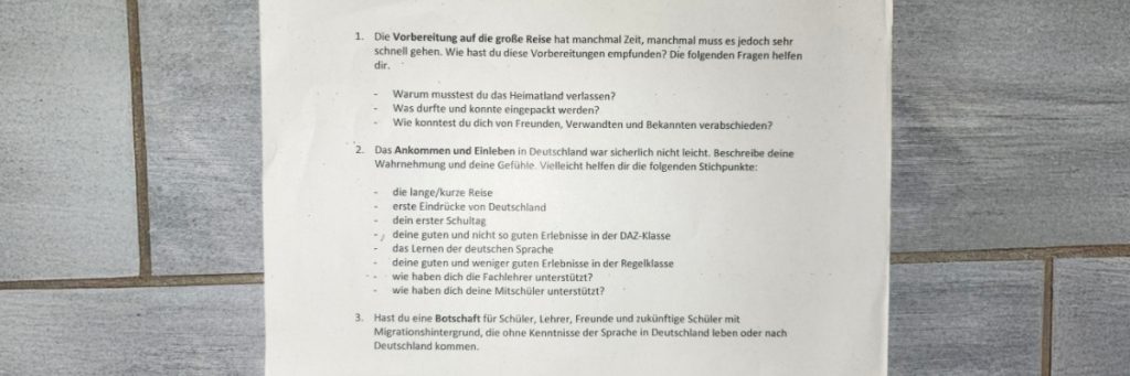 Es ist ein Arbeitsblatt auf einem Kachel-Untergrund zu sehen. Es geht um Fragen zu einer großen Reise, die in Eile geschehen musste.