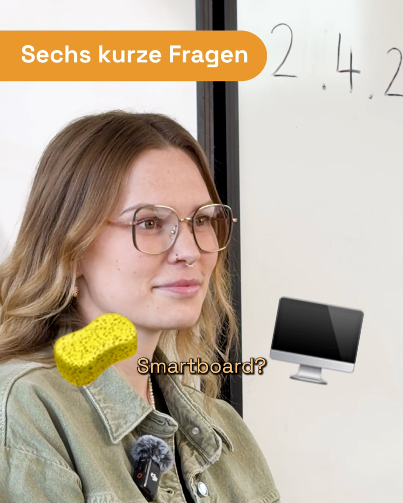 Sechs kurze Fragen: Eine Lehrerin mit Brille und gelbem Smiley vor einem Smartboard. Orange Banner und weiße Wand mit Zahl 2.